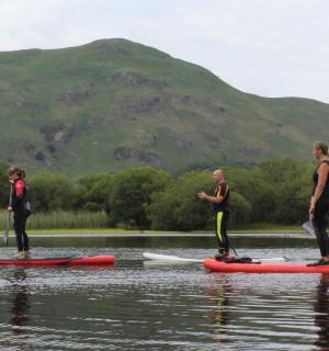 three people are standing on paddle boards in the water