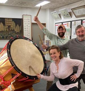 two men and a woman standing next to a drum
