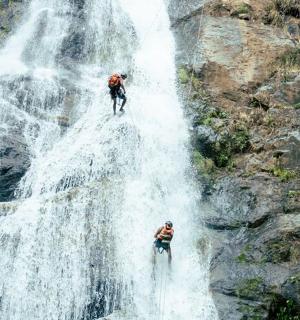 two people standing on top of a waterfall