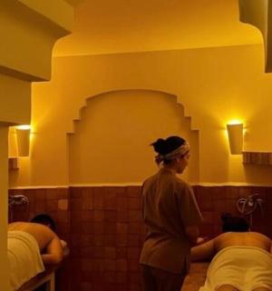 a woman standing in a bathroom with two beds