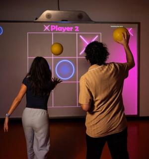 zwei Personen, die in einem Raum ein Videospiel spielen
