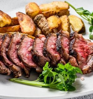 a plate of food with meat and potatoes and greens
