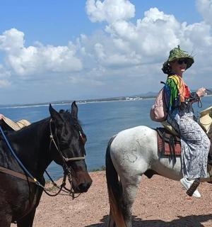 two women riding on horses next to the water