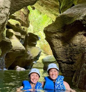 two people swimming in a river in a cave