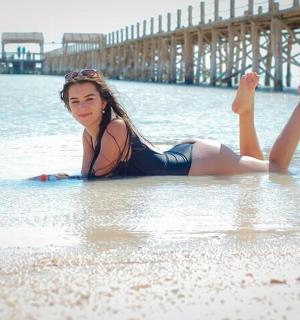 一名女子躺在沙滩上的水中