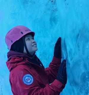 一个穿着粉色夹克的小孩站在墙边