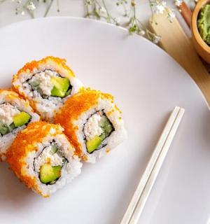 a white plate with sushi on it with chopsticks