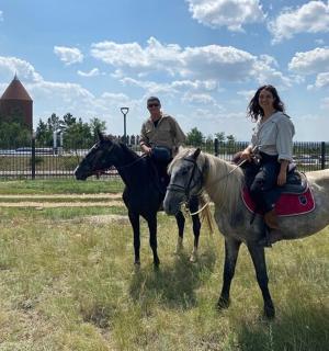 a man and a woman riding horses in a field