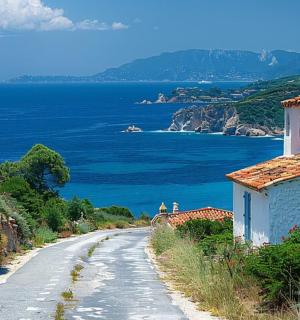 a dirt road with a house and the ocean