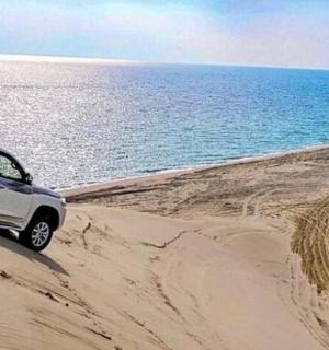 samochód jadący po piaszczystej plaży w pobliżu oceanu