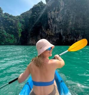 一名女子在水中划着皮划艇，手里拿着桨