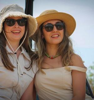 two women wearing hats and sunglasses sitting next to each other