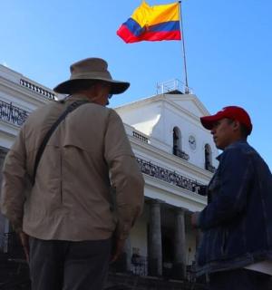 两名男子站在一栋建筑物前,手里拿着一面旗帜