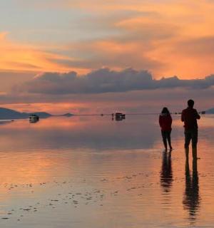 a couple standing on the beach watching the sunset