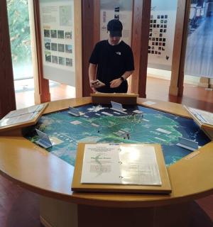 a man standing in front of a table in a museum