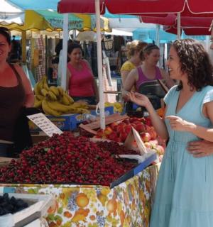 um grupo de pessoas em pé ao redor de uma barraca de frutas em um mercado