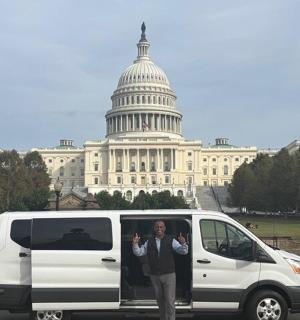 a man standing next to a white van in front of the capitol building