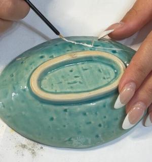 a person ispainting a green bowl with a thread