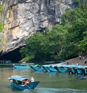 a group of blue boats in a river near a cave