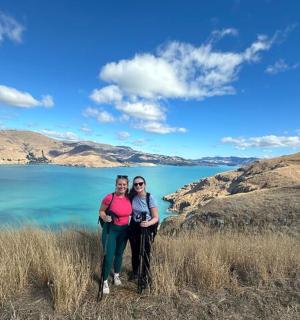 two people standing on a hill near a body of water