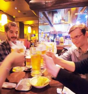 a group of people sitting around a table drinking beer