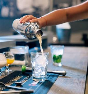a person pouring a drink into a glass on a table