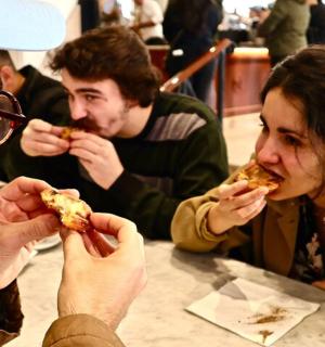 a group of people sitting at a table eating pizza
