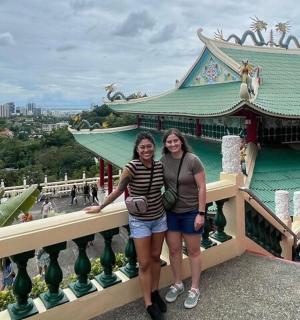 duas mulheres em pé na sacada em frente a um prédio