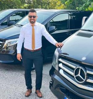 a man wearing an orange tie standing next to cars