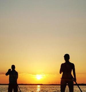 deux personnes rament dans l'eau au coucher du soleil