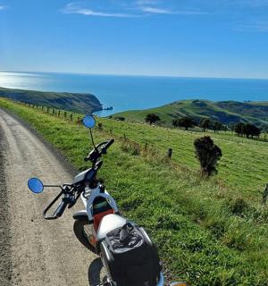 一辆摩托车停在海边附近的一条土路上。