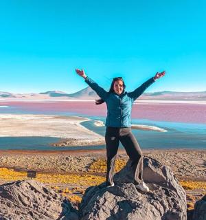 a woman standing on a rock with her arms outstretched