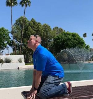 чоловік сидить на лавці перед фонтаном