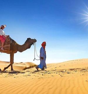 a man and a woman riding a camel in the desert