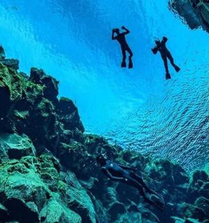 two people swimming in the water near the rocks