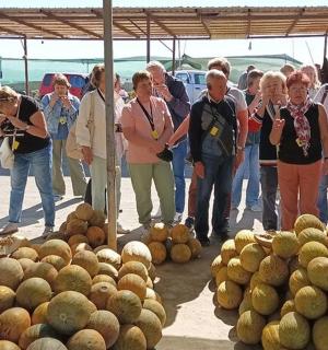 一群人站在一堆甜瓜旁边