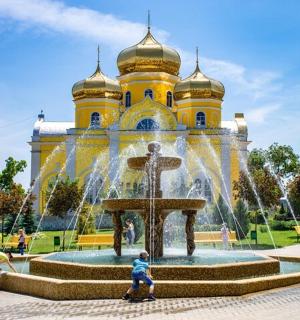 a fountain in front of a yellow building