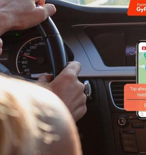 a person driving a car with a cell phone on the dashboard