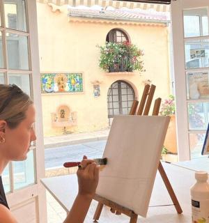 a woman painting on an easel with a paintbrush