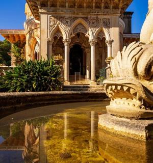 a stone lion statue sitting next to a pool of water