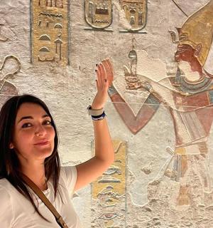 a woman standing in front of a wall with a mural
