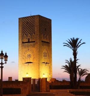 Hodinová věž při západu slunce s palmami a pouliční lampou