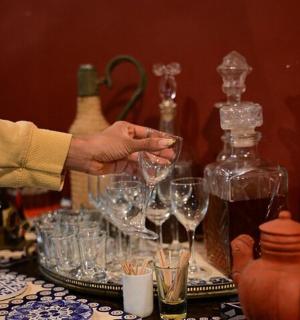 一个人手里拿着酒杯，桌子上放着几瓶酒。