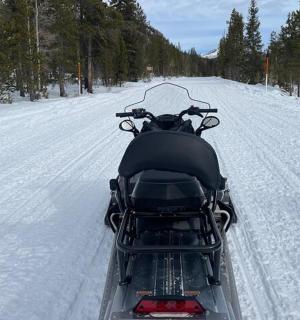 a snowmobile driving down a snow covered road