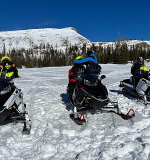three people riding on snow motorcycles in the snow