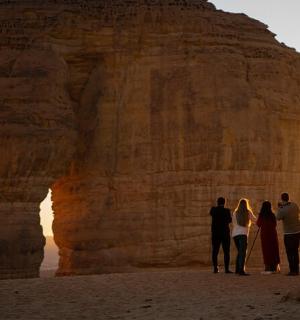a group of people standing in front of a rock formation