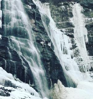 a waterfall with snow on the side of a mountain