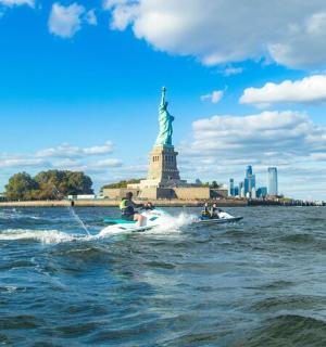 一群人乘坐一艘船，在自由女神像附近的水域中。
