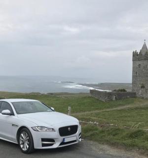 a white car parked on a road next to a castle