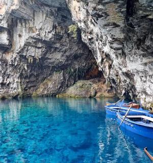 un vaixell blau a l'aigua al costat d'un penya-segat
